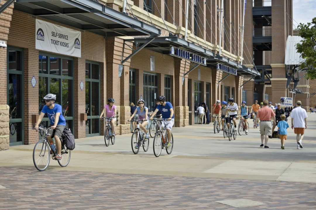 Cyclists ride past Coors Field