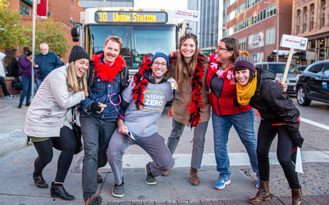 Six smiling people and an RTD bus