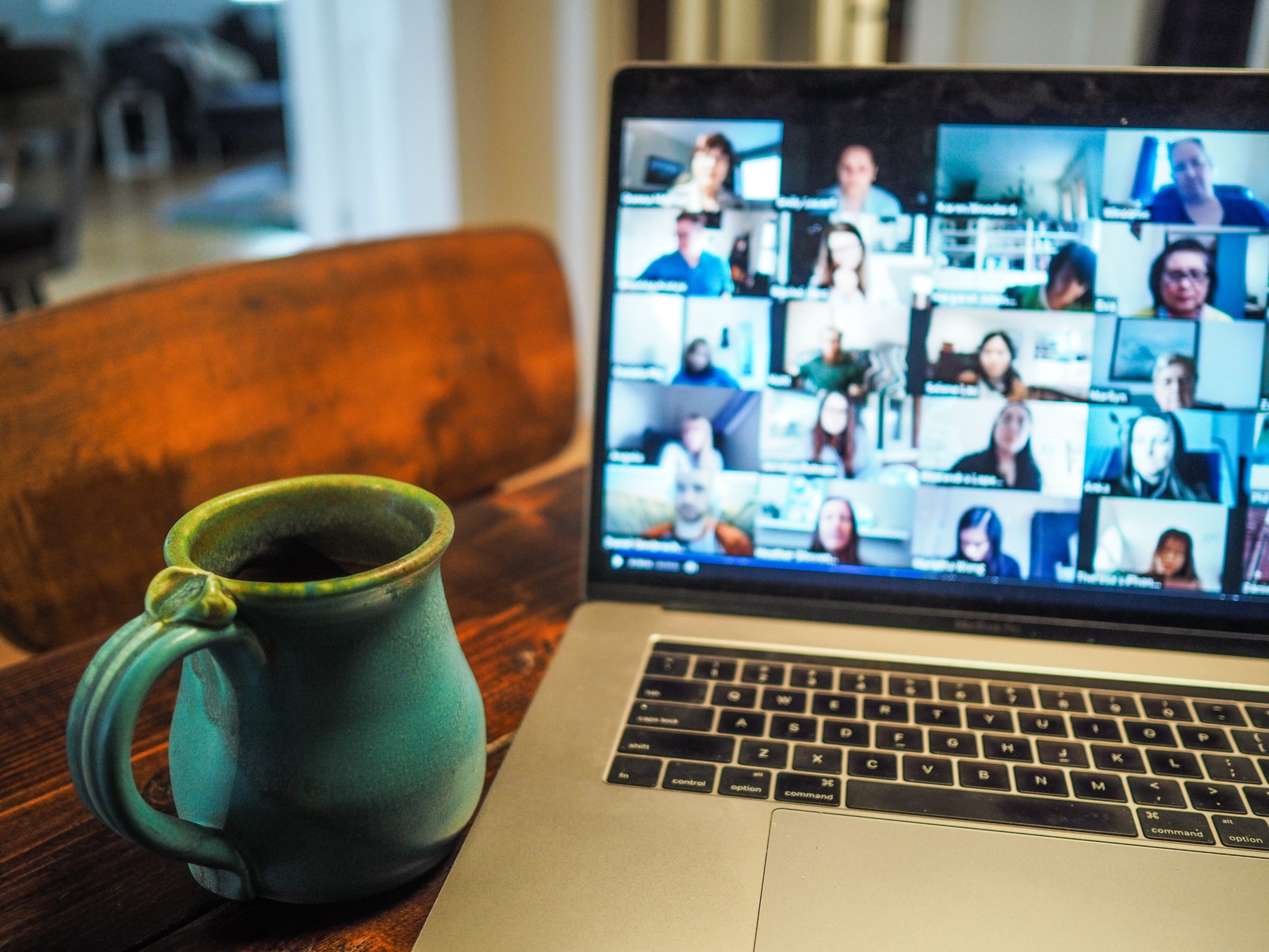 Coffee mug next to laptop showing virtual meeting attendees