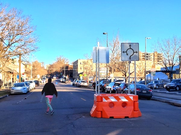 Person walking near barricades on shared street E 11th Ave at Emerson St January 2021