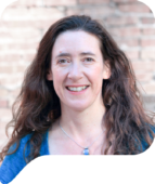 A speech bubble shaped cut out of a woman with long, curly brown hair and brown eyes smiles at the camera in front of a brick wall