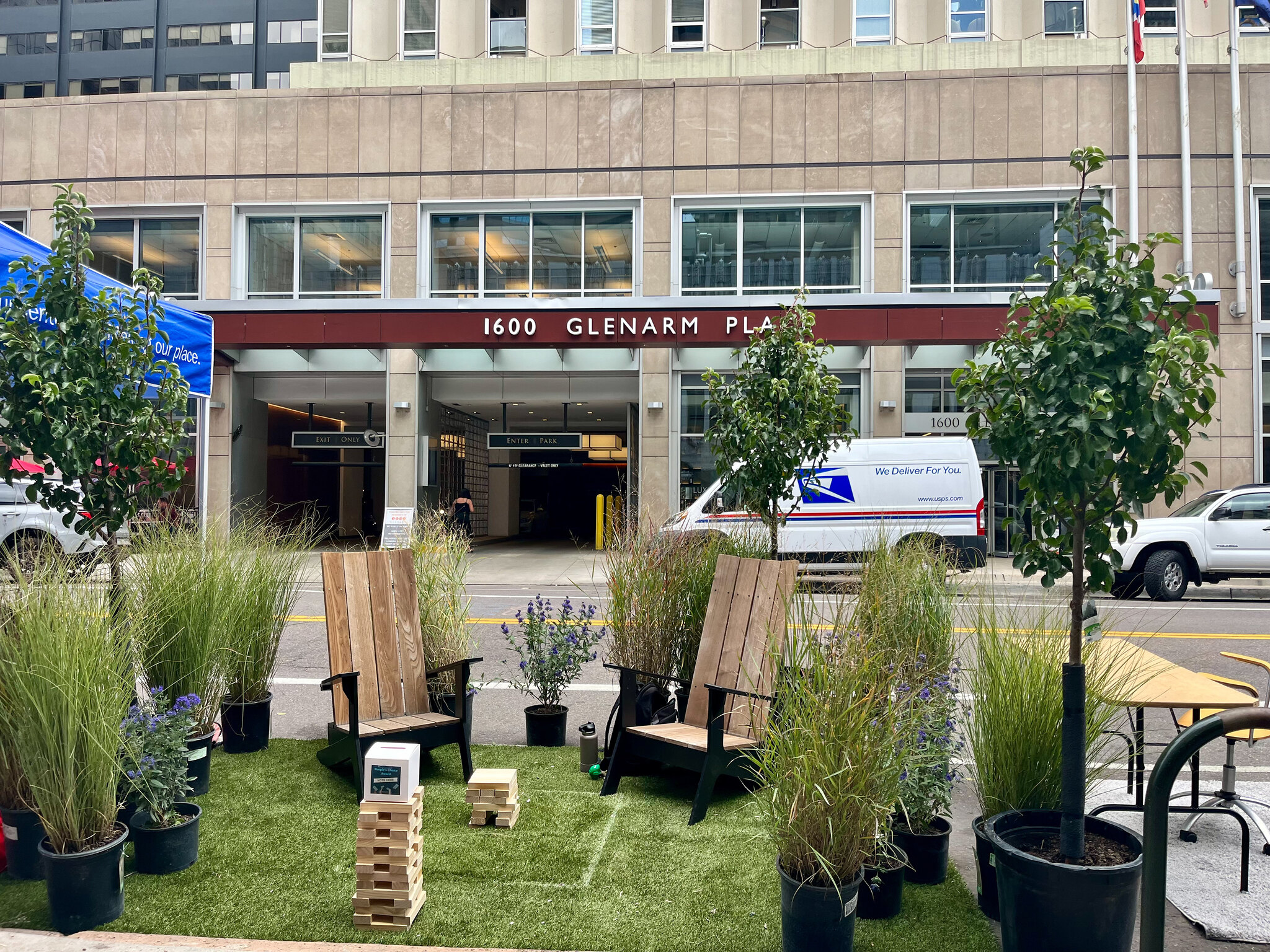 A small grass lawn, chairs, yard games and plants taking up a street parking space in Denver.