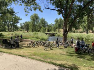 A group of bicyclists hang out with their bikes parked at a local park.