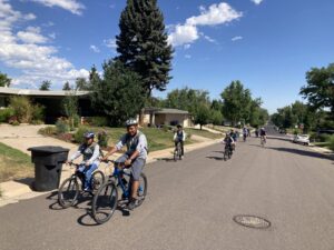 Several kids bike down a neighborhood street together.