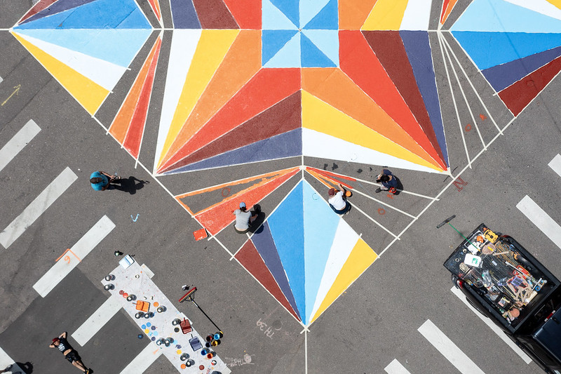 An aerial shot of an intersection mural being painted on the ground.