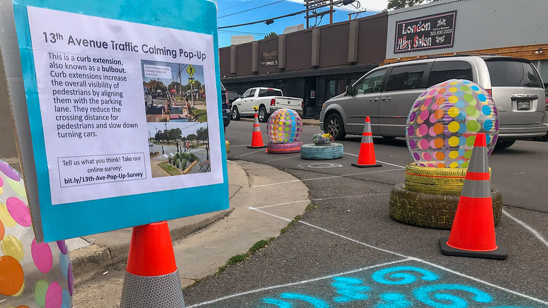 A sign near a pop-up traffic calming demonstration with a DIY bulbout that explains what bulbouts are.