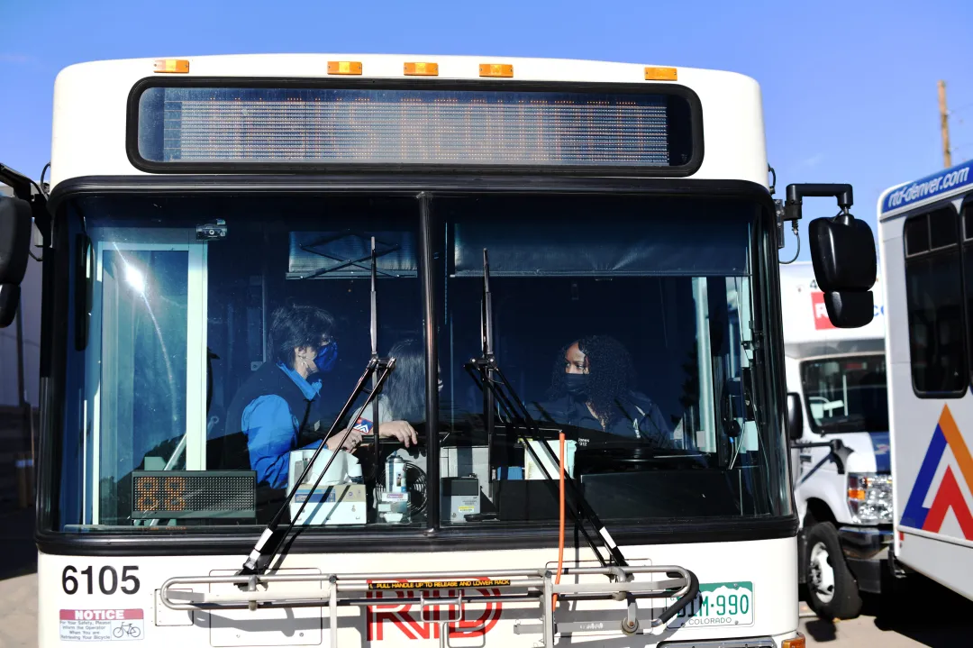Three RTD bus drivers sit in the front of a bus during a training session.