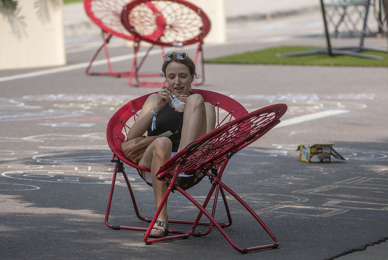 A person sitting in a moon chair on a street.