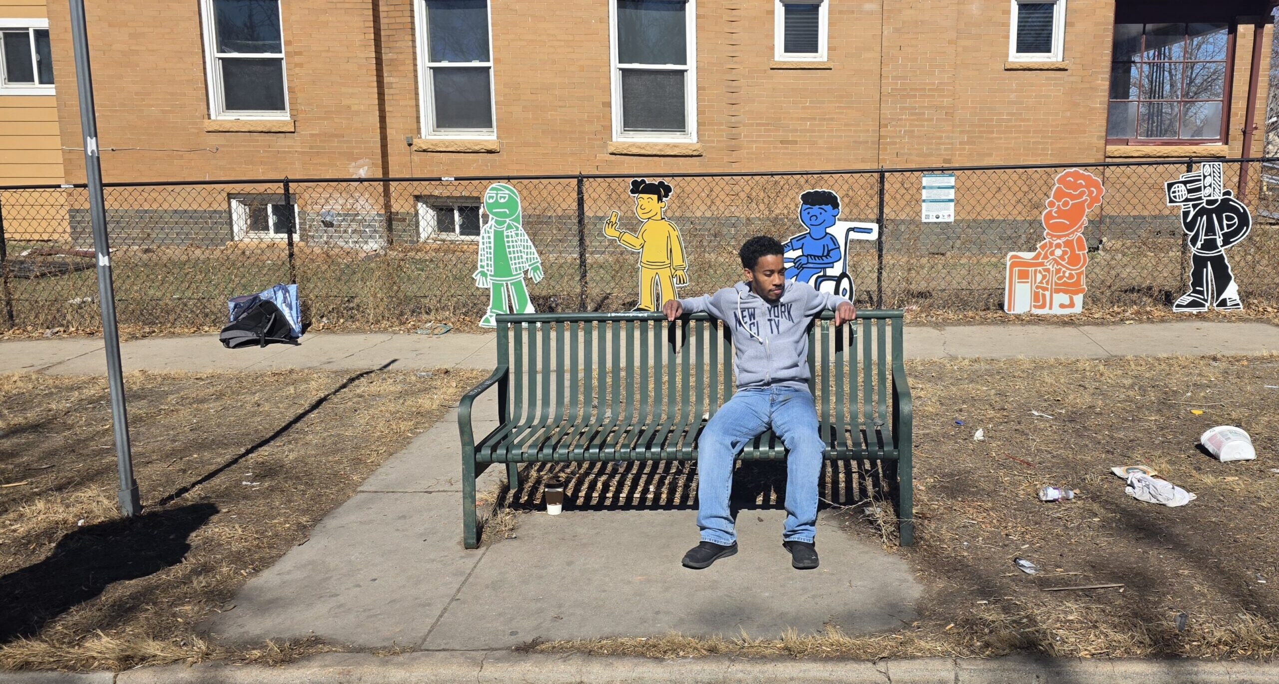Artist AJ Kiel sits in front of his art piece installed at MLK Jr Boulevard and York Street