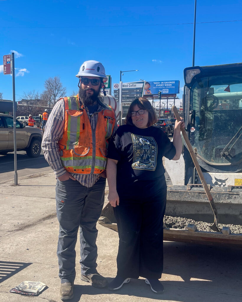 Artist Nicole Vanston stands with a construction crew member who helped pour concrete needed to install her art near the bus stop at Colfax and Winona