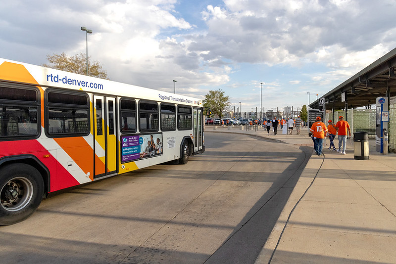 Image of people wearing Broncos jerseys walking near an RTD Bus