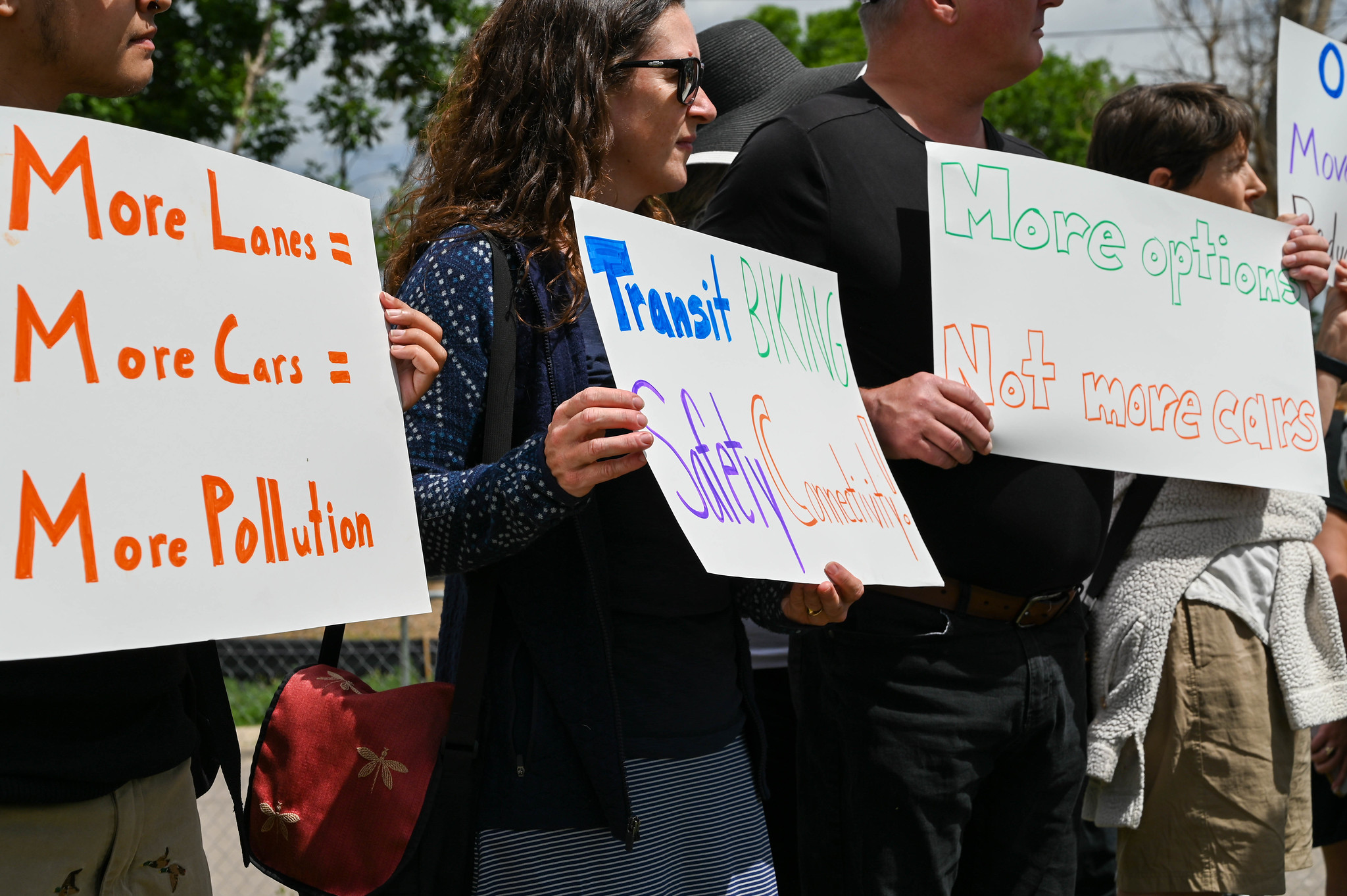 People holding signs advocating for fewer cars and more mobility options.